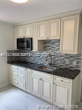 16121 Southwest 141st Avenue Miami, FL 33177 - Photo 5 of 11 a kitchen with granite countertop a sink a stove and cabinets