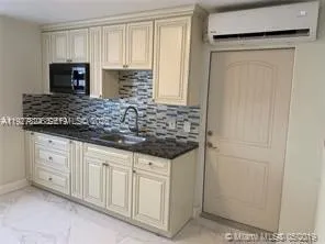a kitchen with granite countertop white cabinets and black appliances