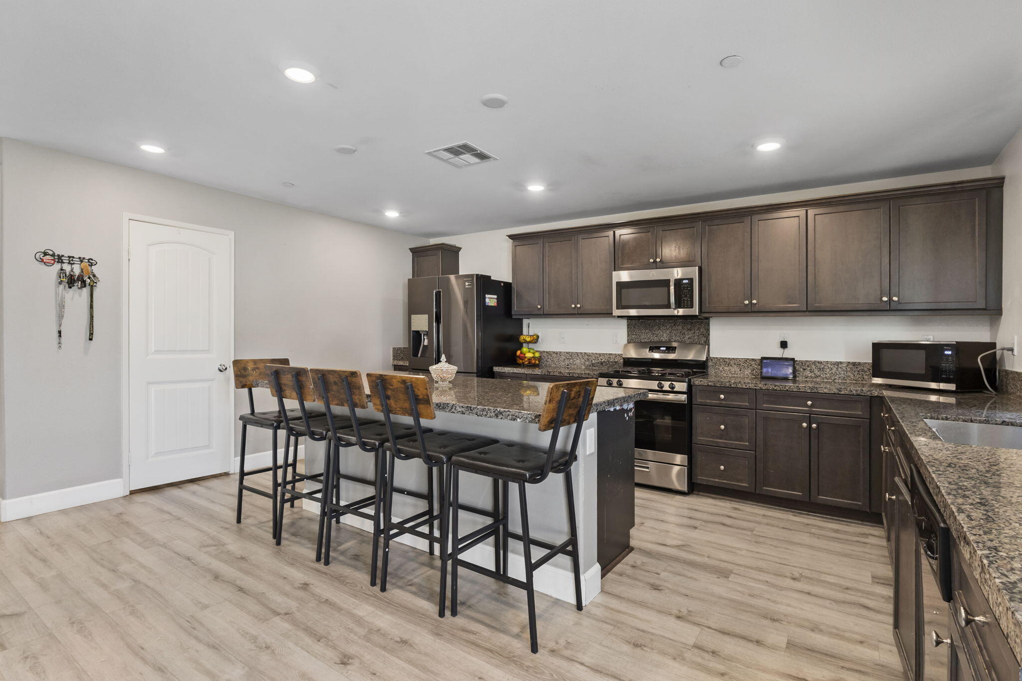 32486 Roman Warren Way Winchester, CA 92596 - Photo 22 of 45 a kitchen with stainless steel appliances granite countertop a stove top oven a sink dishwasher a dining table and chairs with wooden floor