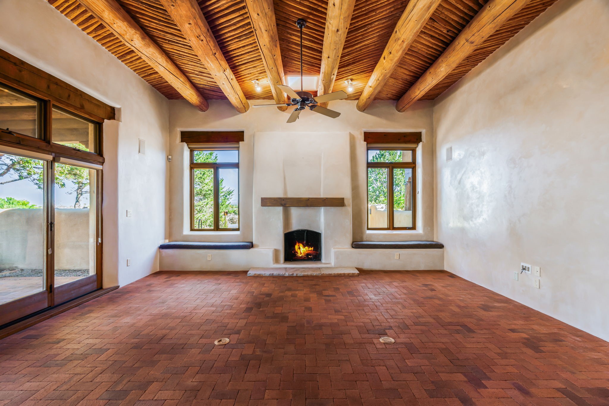 10 Antigua Road Santa Fe, NM 87508 - Photo 12 of 57 Brick floors in living room with high viga and latilla ceilings and Rumsford style fireplace