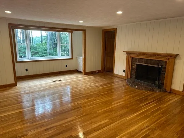 a view of an empty room with window and wooden floor