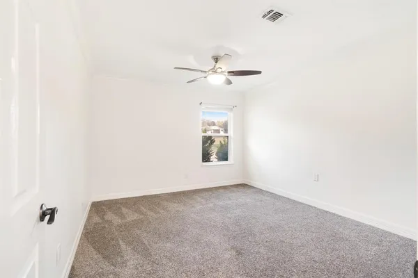 an empty room with a window and a ceiling fan