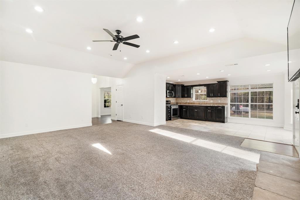 220 Laredo Drive Reno, TX 75462 - Photo 7 of 24 a view of a livingroom with a ceiling fan a kitchen space with a sink and windows