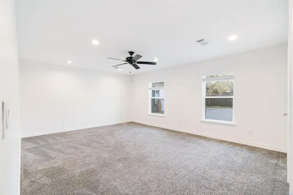 an empty room with windows and fan