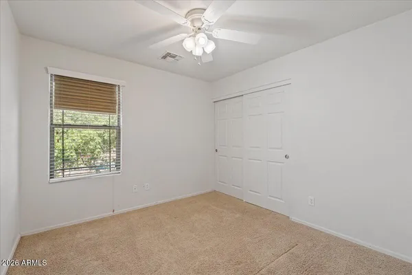 an empty room with a chandelier fan and windows