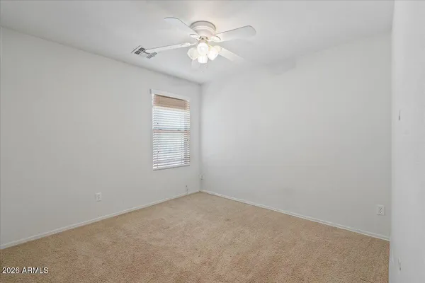 an empty room with a chandelier fan and windows