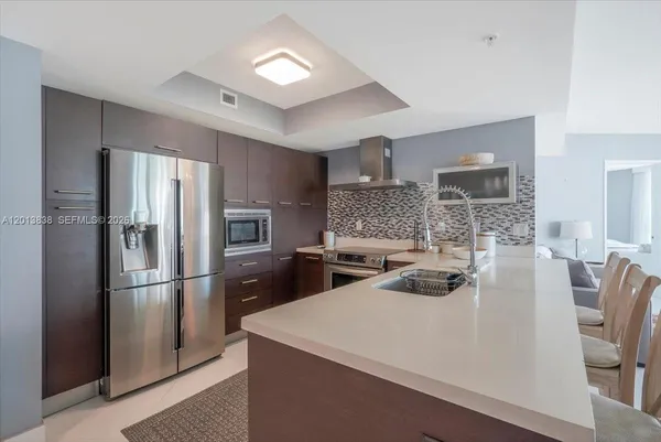 a kitchen with stainless steel appliances a refrigerator a sink a stove a table and chairs