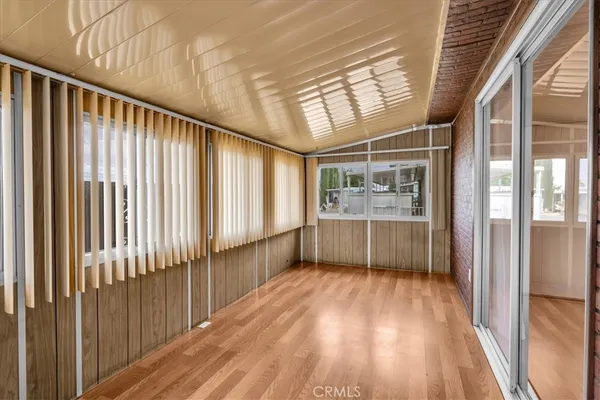 a view of empty room with wooden floor and floor to ceiling window