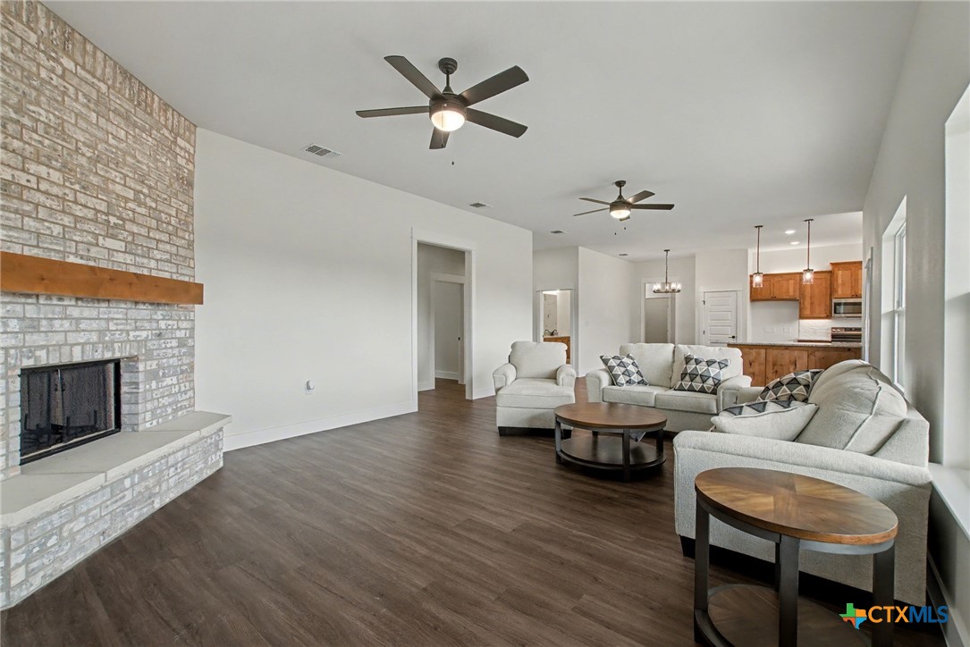 425 County Road 3152 Kempner, TX 76539 - Photo 7 of 27 a living room with couches a fireplace and a kitchen view with wooden floor