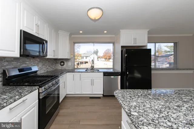 a kitchen with stainless steel appliances granite countertop a refrigerator stove microwave and sink