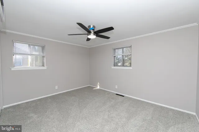 an empty room with a window and a fan