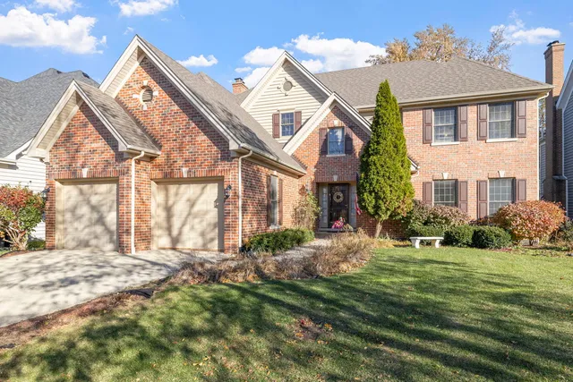 a view of a white house next to a yard with big trees