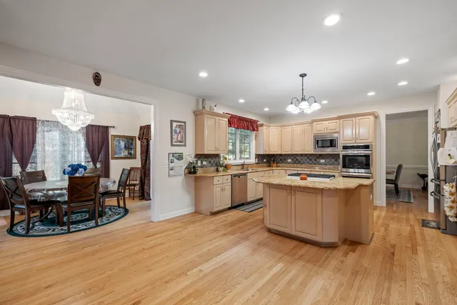 a kitchen with kitchen island a stove a refrigerator a dining table and chairs with wooden floor