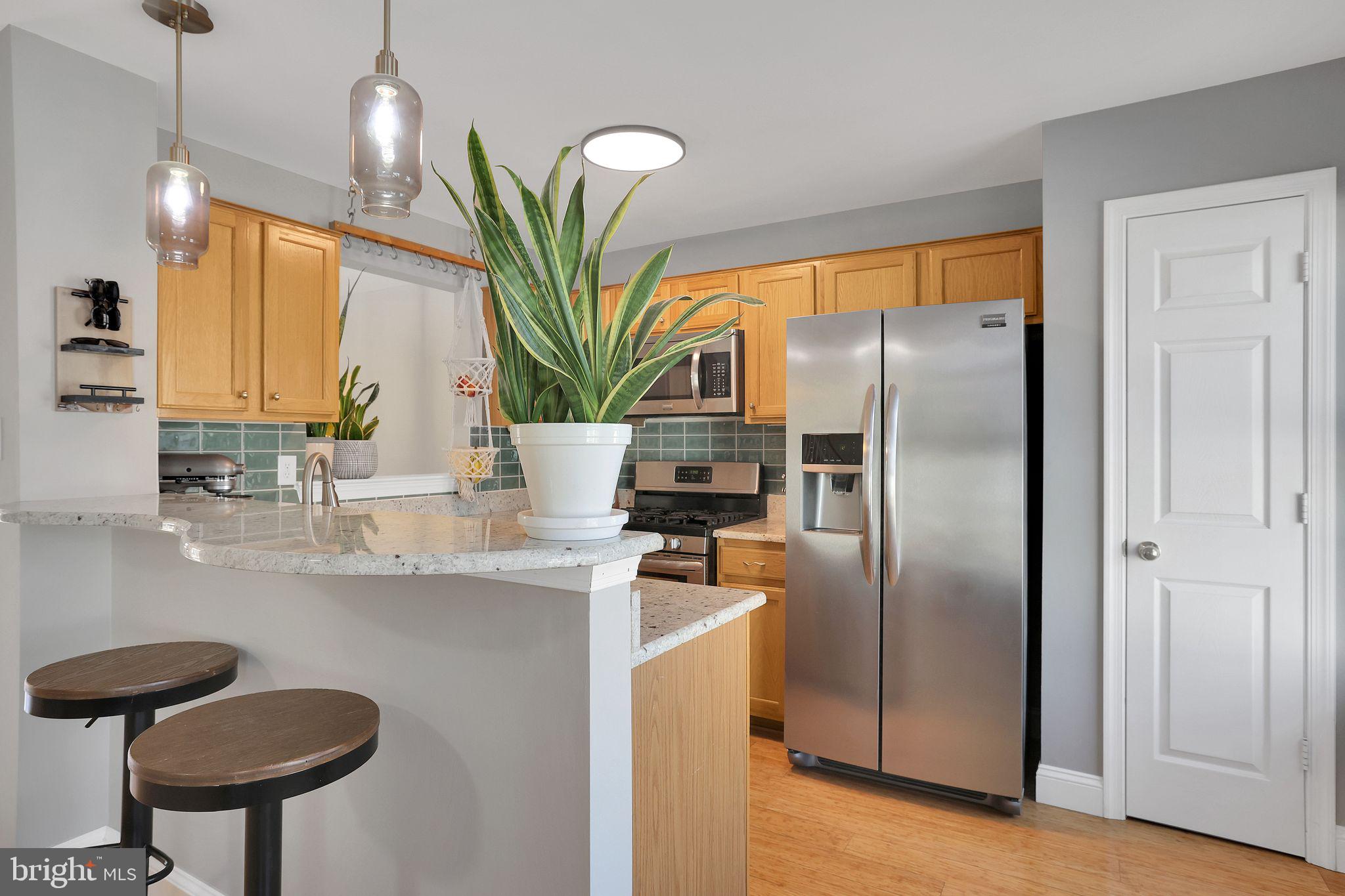 22952 Regent Terrace Sterling, VA 20166 - Photo 15 of 64 a kitchen with stainless steel appliances granite countertop a refrigerator a sink a stove and a wooden floors