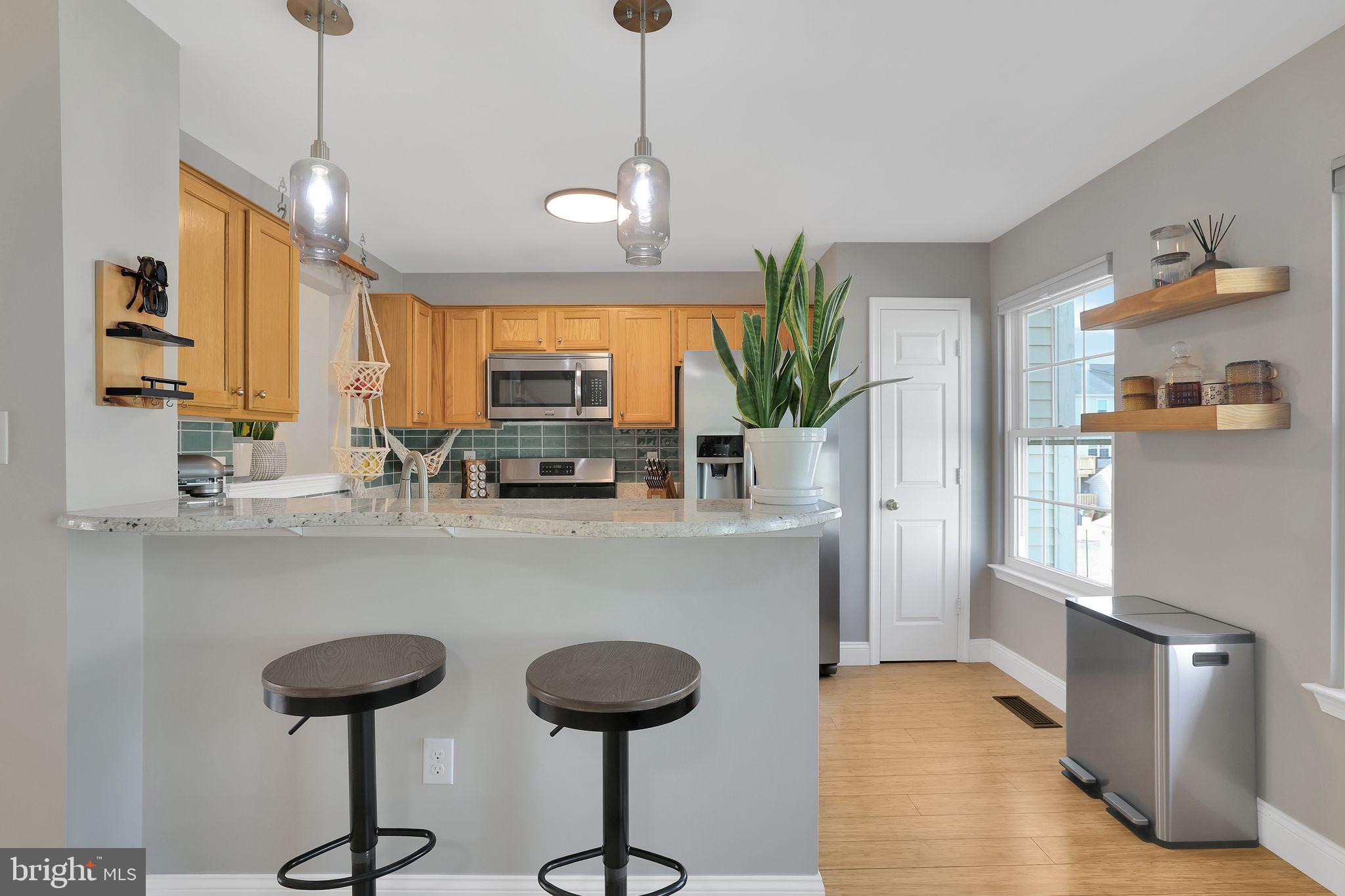 22952 Regent Terrace Sterling, VA 20166 - Photo 19 of 64 a kitchen with stainless steel appliances granite countertop a sink a stove a refrigerator a dining table and chairs with wooden floor