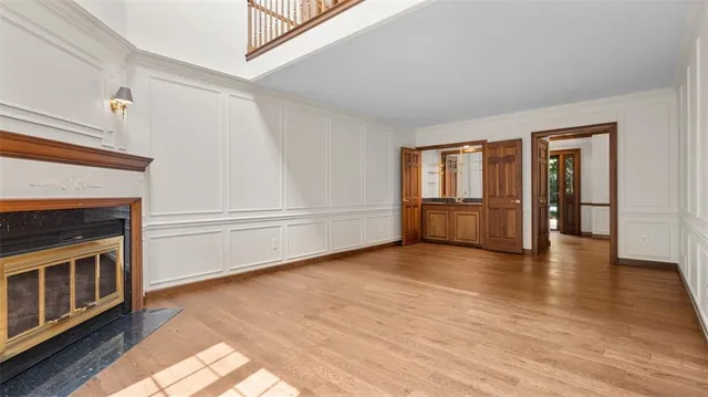 an empty room with wooden floor fireplace and windows