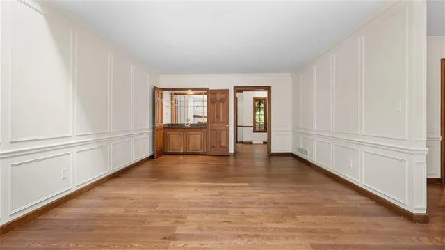 a view of an empty room with a window and wooden floor