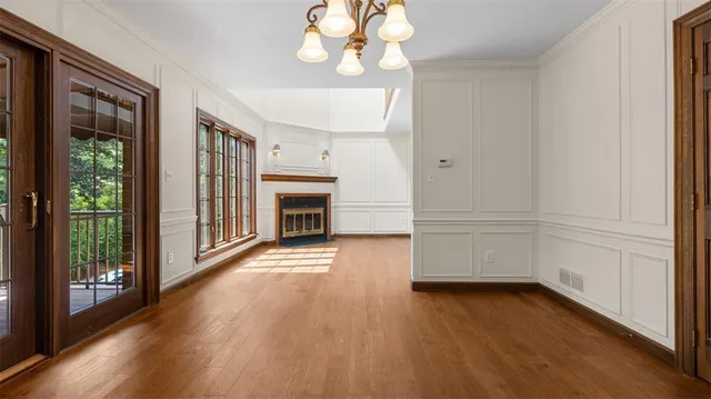 an empty room with wooden floor fireplace and windows