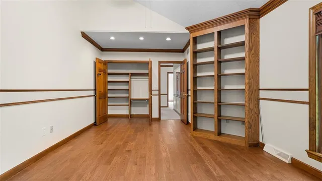 an empty room with wooden floor closet and windows