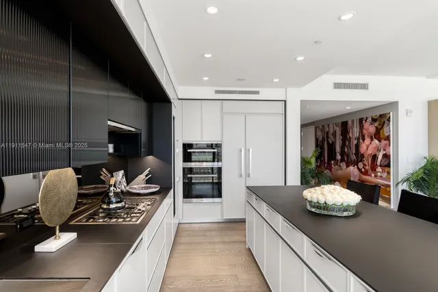 a kitchen with stainless steel appliances kitchen island granite countertop a stove and white cabinets