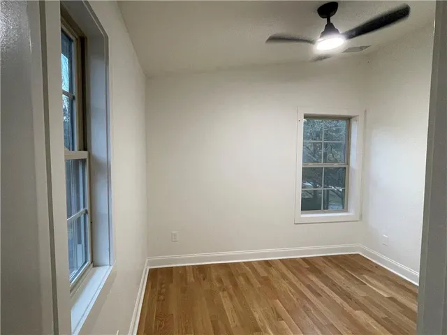 an empty room with wooden floor closet and windows