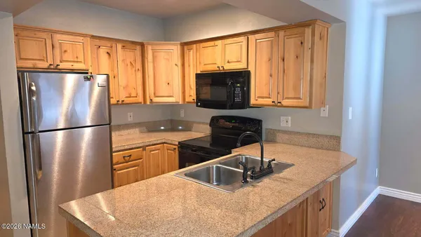 a kitchen with stainless steel appliances granite countertop a refrigerator a sink dishwasher a stove with wooden cabinets