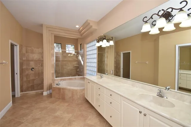 a bathroom with a bathtub a double vanity sink a vanity a window and a mirror