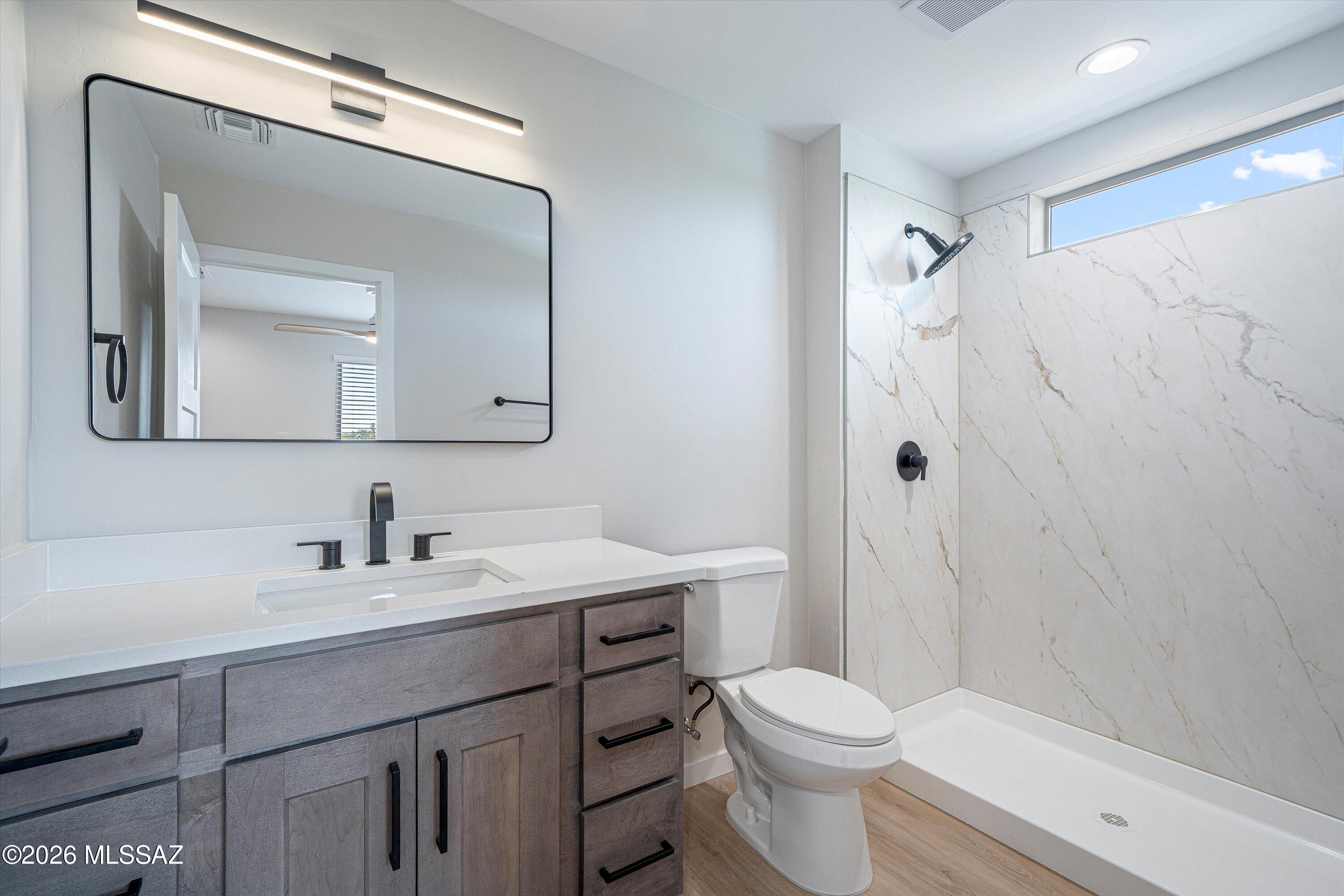739 North Queen Avenue, Unit 2 Tucson, AZ 85705 - Photo 9 of 28 a bathroom with a toilet a sink a glass door a shower a mirror and vanity