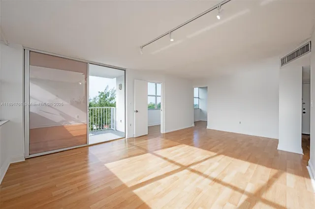 a view of a big room with wooden floor and windows