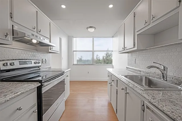 a kitchen with a sink stove top oven and cabinets