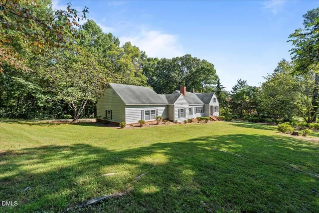 a view of a house with a big yard potted plants and large tree