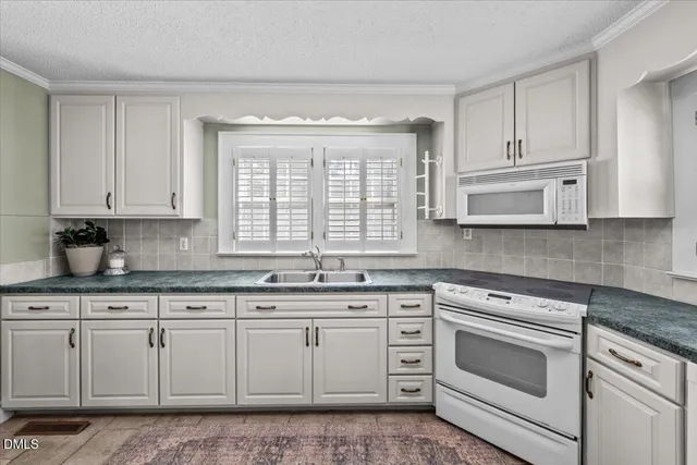 a kitchen with granite countertop white cabinets and white appliances