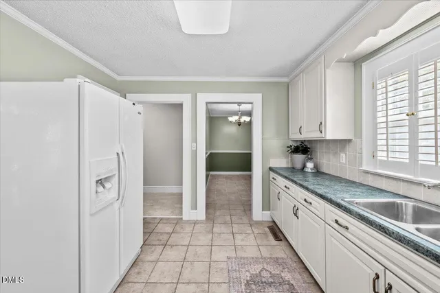 a large white kitchen with a sink and refrigerator