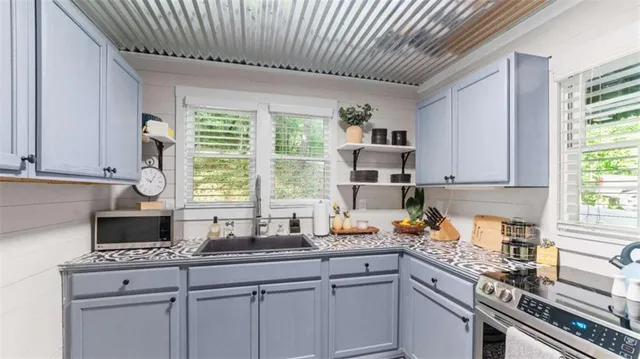 a kitchen with stainless steel appliances a sink a stove cabinets and a window