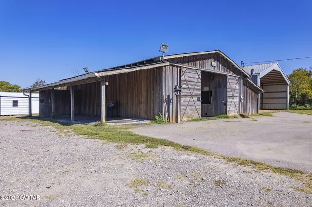 a view of a wooden house with a yard and large tree