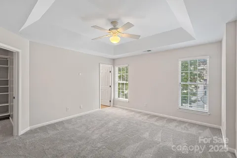 an empty room with windows and chandelier fan