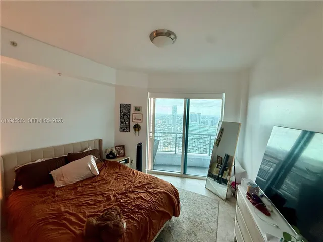 a bedroom with a bed a flat screen tv and a large window