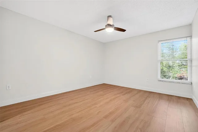 a view of an empty room with wooden floor and a window