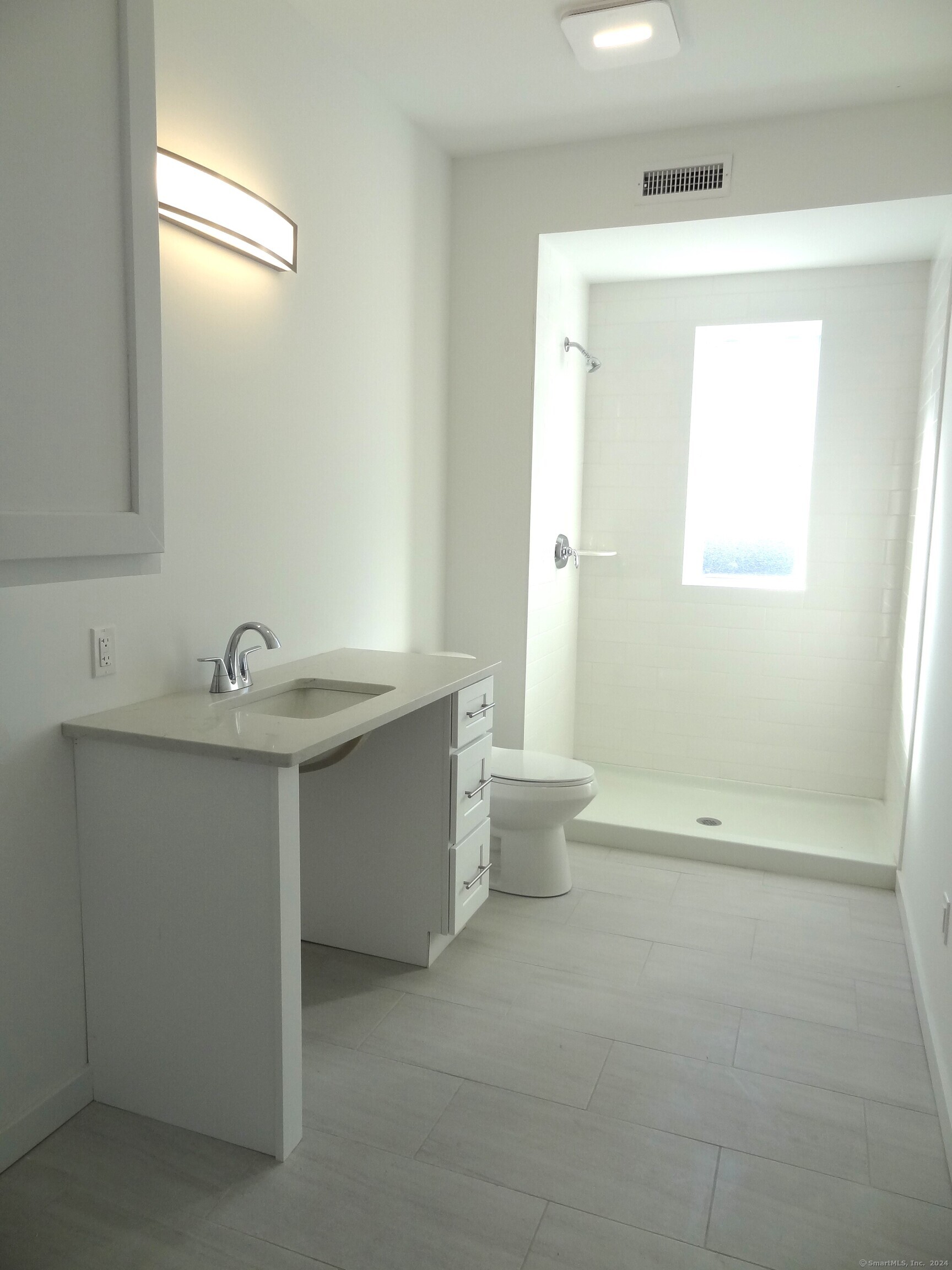 2806 Fairfield Avenue, Unit 307 Bridgeport, CT 06605 - Photo 10 of 24 a bathroom with a sink a toilet and a mirror