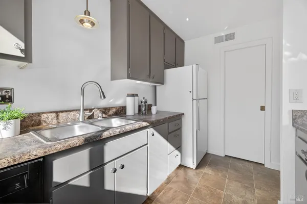a kitchen with granite countertop a sink stove and refrigerator