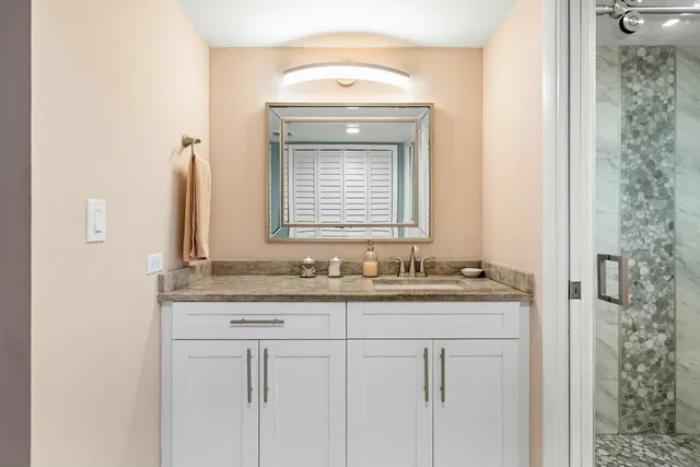 a bathroom with a granite countertop sink and a mirror