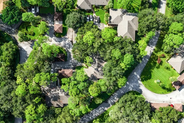 an aerial view of residential house with outdoor space and trees all around