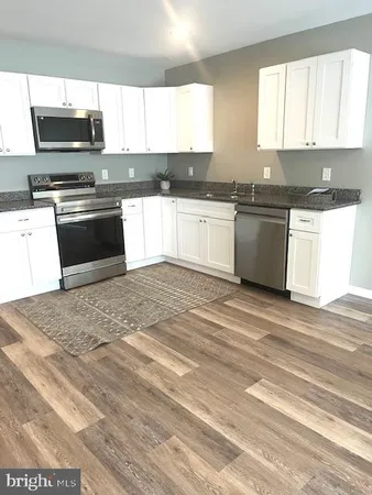 a kitchen with granite countertop a sink cabinets and stainless steel appliances