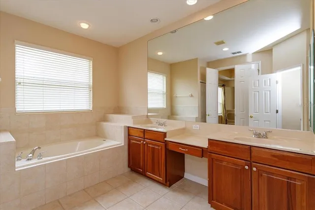 a bathroom with a tub sink double vanity granite and tub