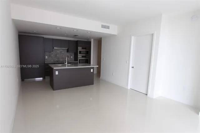a living room with stainless steel appliances a kitchen island a sink a stove and a refrigerator