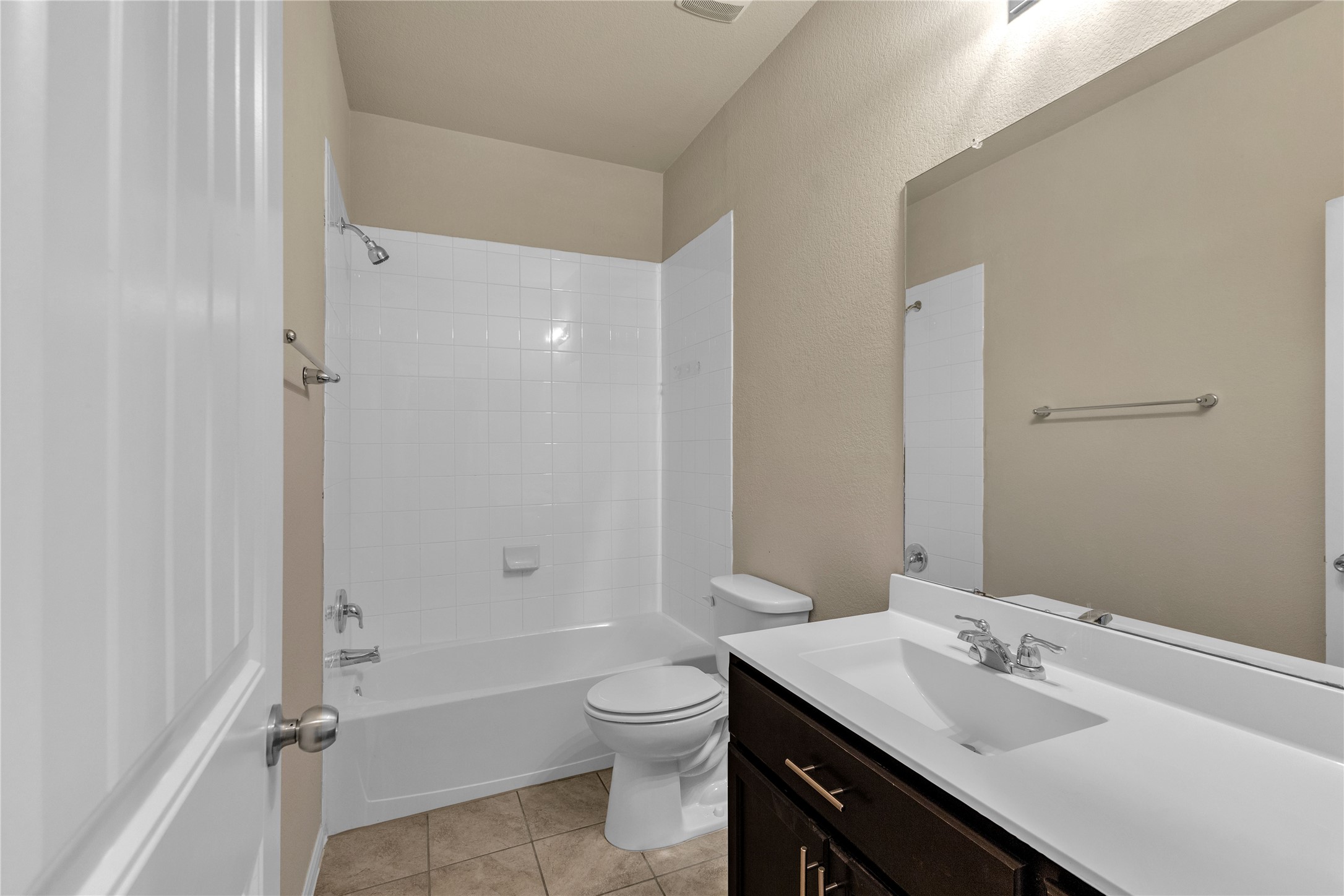 2880 Donnell Drive, Unit 2003 Round Rock, TX 78664 - Photo 20 of 31 Full bathroom featuring a white tile shower-over-tub, dark wood-finish vanity with an integrated sink, and an expansive wall-mounted mirror