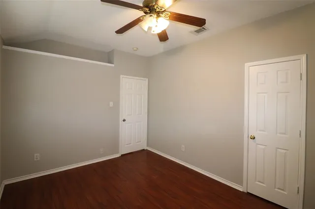 an empty room with wooden floor and fan