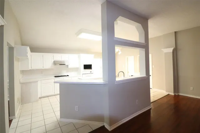 a kitchen with stainless steel appliances granite countertop a refrigerator a sink a stove and white cabinets with wooden floor