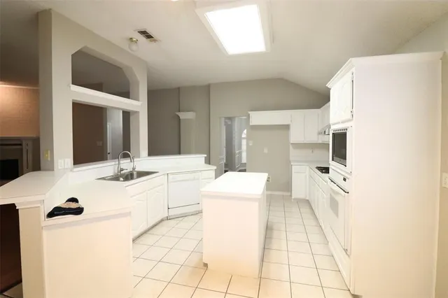 a large white kitchen with a sink a refrigerator and a stove
