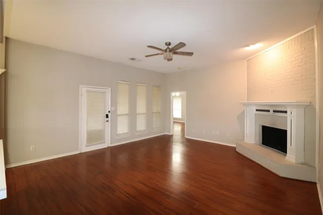a view of an empty room with wooden floor and a fireplace